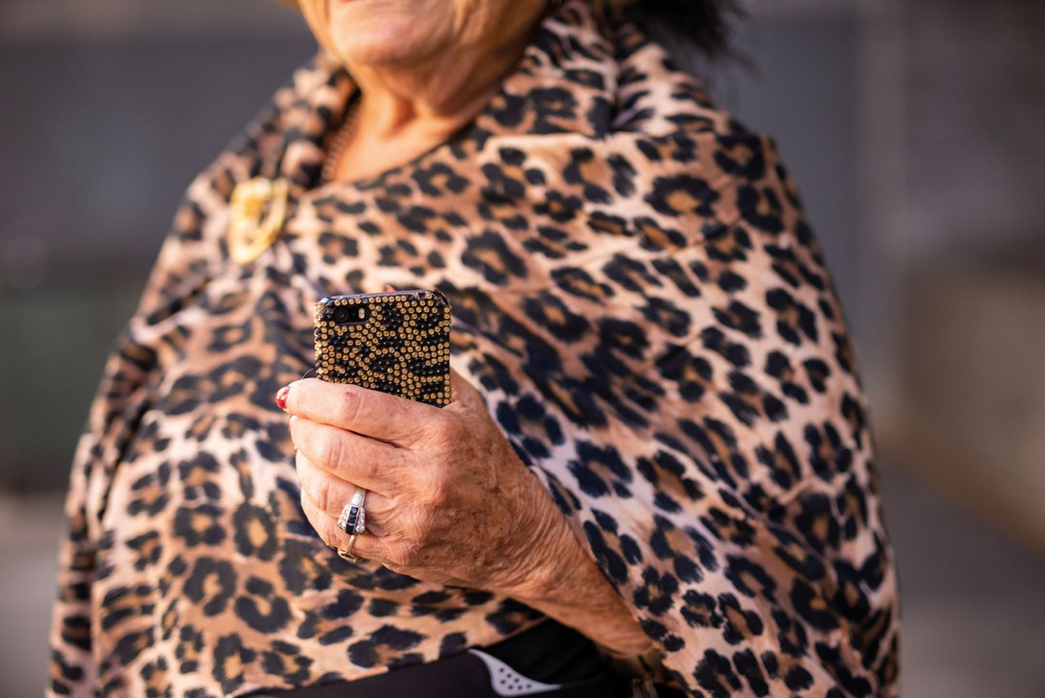 Een vrouw draagt een stola met een luipaard dierenprint en heeft een telefoon met een luipaard dierenprint hoes in haar hand